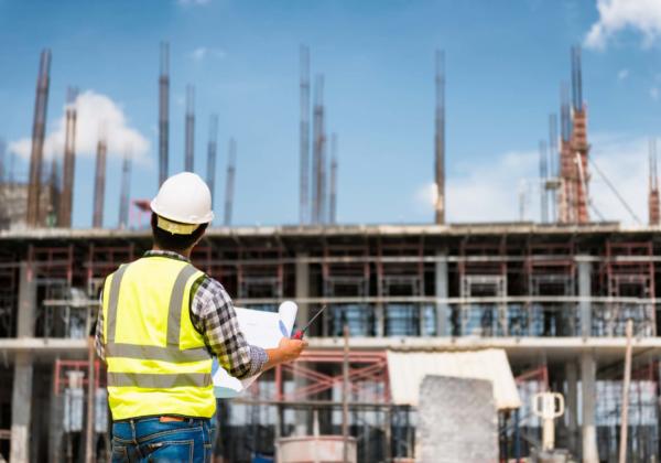 Engineering Consulting People On Construction Site Holding Bluep
